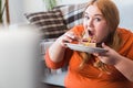 Chubby woman sport at home sitting eating cake hungry watching movie in laptop