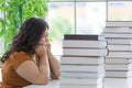 Chubby woman student sitting and looking on a stack of books on a table with anxious in a room of the house. Study and work from Royalty Free Stock Photo