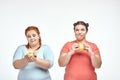 Chubby women: one woman is holding a sandwich,another one holding an apple