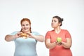 Chubby women: one woman is holding a sandwich,another one holding an apple