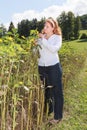 Chubby young red-haired woman controls the maturation of a sunflower Royalty Free Stock Photo