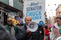 Chuck Schumer standing in front of a crowd, raising a megaphone and talking to them