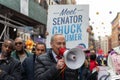 Chuck Schumer standing in front of a crowd, raising a megaphone and talking to them