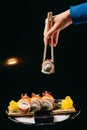 Chuka Roll in Chinese chopsticks in hand on a black background Royalty Free Stock Photo