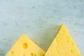 Chunk and Wedge of Alpine Creamy Appetizing Yellow Tilsit and Maasdam Cheese on Scratched Grey Metal Background. Texture