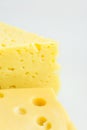 Chunk and wedge of Alpine creamy appetizing yellow Tilsit and Maasdam cheese on white background. Texture with cracks and holes