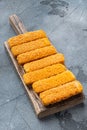 Chunky breaded frozen fish fingers, on wooden cutting board, on gray background Royalty Free Stock Photo