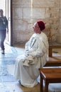 A church attendant in white clothes is sitting on a bench in the Church of Saint Anne in the old city of Jerusalem, Israel