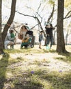 Church backyard with matured tree and load of Easter eggs on green grass field, long line of diverse parent kids waiting Royalty Free Stock Photo