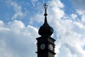 Black metal covered clock tower. white clock face. ornate cross at the top.