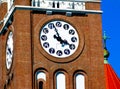 church clock tower closeup detail with black hands. white clock face. brick tower facade Royalty Free Stock Photo