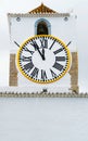 Church clock of a white mediterranean church with roman numerals. Hands showing five minutes to twelve. Time pressure, deadline Royalty Free Stock Photo