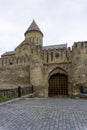 Church dome, high stone defensive wall and wooden gate. Towers on the walls, brick arch. Beautiful metal fence. Svetitskhoveli Royalty Free Stock Photo