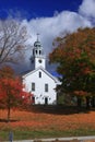 New England church if fall with blue sky and carpet of leaves