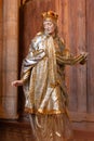In Kutna Hora see a closeup of a statue of a saint with a crown and cross inside the miners` church, St Barbara.