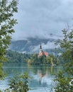 Church of Mary the Queen by Lake Bled, surrounded by dense, magic forest and fog in the morning