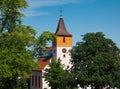 Church with an orange-hued steeple sits amongst lush green trees in the distance Royalty Free Stock Photo