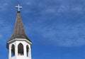 Church roof with metal cross on top and white bell tower with fluffy clouds Royalty Free Stock Photo