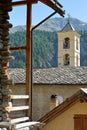 The church of Saint Veran with a traditional wooden house in the foreground and mountains in the background