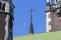 Church spire with a cross in the morning in sunlight against blue sky and half moon. Lviv, Ukraine Royalty Free Stock Photo