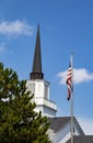 Church and state - Church spire and American flag with evergreen tree and blue sky with clouds Royalty Free Stock Photo