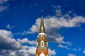 Church steeple against blue sky filled with fluffy white clouds