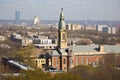 church, with steeple and bell tower, surrounded by bustling cityscape