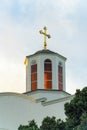 Church steeple with red interior and gold metal cross on roof with white exterior paint on chruch building in late Royalty Free Stock Photo