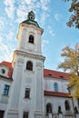 The church is surrounded by trees and has a blue sky in the background. The bell tower of the Strahov Monastery against the blue Royalty Free Stock Photo