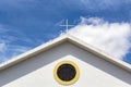 Church top with window and cross and blue sky with clouds