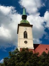 a church tower surrounded by trees under a blue sky with clouds Royalty Free Stock Photo