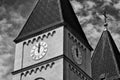 church tower with white round clock. stucco exterior wall. black and white image. arches and shadows. twelve o`clock PM