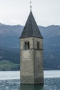 Church under water, drowned village, mountains landscape and peaks in background. Reschensee Lake Reschen Lago di Resia. Royalty Free Stock Photo