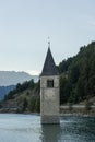 Church under water, drowned village, mountains landscape and peaks in background. Reschensee Lake Reschen Lago di Resia. Royalty Free Stock Photo