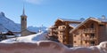 Church and wooden houses in Tignes village ski resort, France, in Winter, with a clear blue sky.