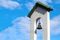 Churchbell in white wall of church tower. Catholic church building.