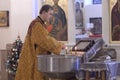 Churchman lights candles in a rural church during serving for the Nativity of Christ