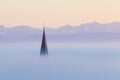 Churchtower above the fog, swiss alps in background