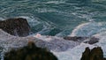 Churning sea washing crag dusk environment closeup. Swirling aqua hitting shore