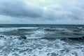 Stormy skies over angry seas, with white-capped waves crashing to the sandy shore Royalty Free Stock Photo