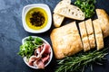 Ciabatta, pepper oil, jamon ham serrano, arugula, rosemary, slate background Royalty Free Stock Photo