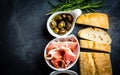 Ciabatta, pepper oil, jamon ham serrano, arugula, rosemary, slate background Royalty Free Stock Photo