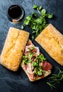 Ciabatta sandwich with jamon ham, arugula. red wine, slate background Royalty Free Stock Photo