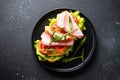 Ciabatta sandwich with lettuce, cheese, tomatoes and ham on black table. Royalty Free Stock Photo