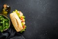 Ciabatta sandwich with lettuce, cheese, tomatoes and ham on black table. Royalty Free Stock Photo