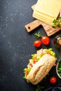 Ciabatta sandwich with lettuce, cheese, tomatoes and ham on black table. Royalty Free Stock Photo