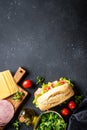 Ciabatta sandwich with lettuce, cheese, tomatoes and ham on black table. Royalty Free Stock Photo