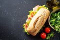 Ciabatta sandwich with lettuce, cheese, tomatoes and ham on black table. Royalty Free Stock Photo