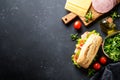 Ciabatta sandwich with lettuce, cheese, tomatoes and ham on black table. Royalty Free Stock Photo