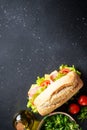 Ciabatta sandwich with lettuce, cheese, tomatoes and ham on black table. Royalty Free Stock Photo